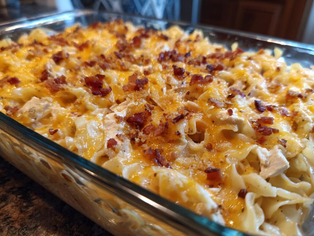 Overhead shot of a cheesy Crack Chicken Casserole Recipe in a glass baking dish, topped with bacon.