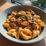Bowl of Creamy Paprika Steak Shells, featuring pasta shells, sliced steak, creamy paprika sauce, and fresh herbs.