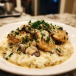 A plate of Creamy Smothered Chicken and Rice, topped with mushrooms and parsley.