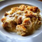 A serving of Creamy Swiss Chicken Casserole with a golden brown topping on a white plate.