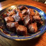 A serving of tender Crockpot Steak Bites, seasoned and cooked to perfection, presented on a decorative blue plate.