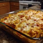 Close-up of a cheesy Easy Chicken Fajita Casserole in a glass baking dish on a kitchen counter.