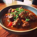 A bowl of hearty Egyptian Beef Goulash, garnished with fresh parsley, ready to be served.