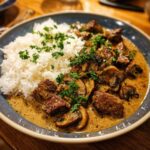 A plate of Gordon Ramsay Beef Stroganoff with rice, mushrooms, and parsley garnish.