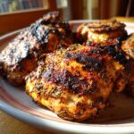 Close-up of grilled chicken thighs marinated in Greek Chicken Marinade, showing herbs and char marks.