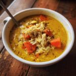 A bowl of Lemon Ginger Turmeric Chicken and Rice Soup with carrots, chicken, and rice.