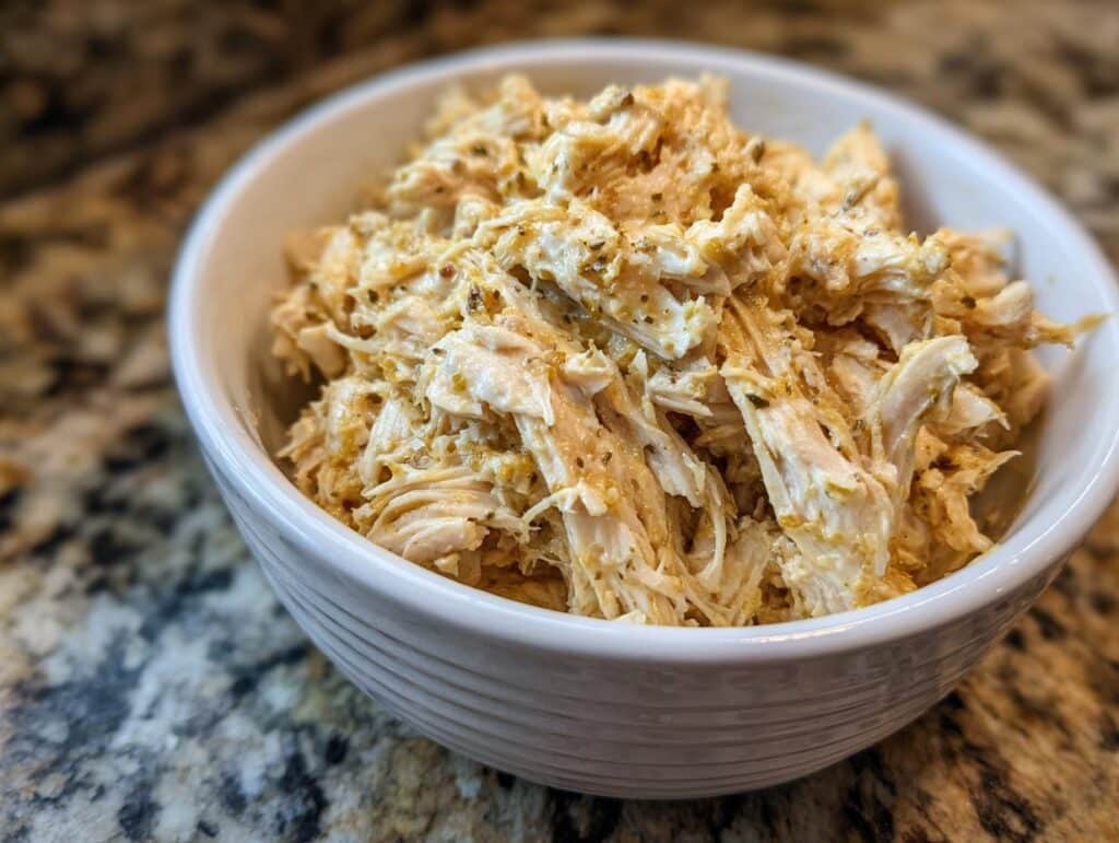 Close-up of Ranch Chicken Crock Pot in a white bowl, showcasing the shredded chicken and creamy ranch seasoning.