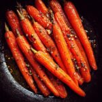 Close-up of glazed carrots with herbs, showcasing a key ingredient for Raw Carrot Salad.