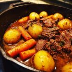 Close-up of Red Wine-Braised Beef Stew with Potatoes and Carrots in a cast iron pot.