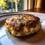 A single Rosemary Lemon Chicken Patties on a white plate, garnished with fresh rosemary.