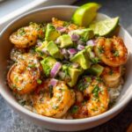 A vibrant Shrimp and Avocado Bowl with rice, grilled shrimp, diced avocado, red onion, and lime wedges.