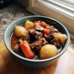 A bowl of hearty Slow Cooker Beef Bourguignon with beef, carrots, potatoes, and mushrooms.