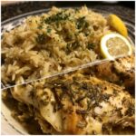 A plate of Slow Cooker Lemon Herb Chicken Rice, featuring chicken, rice, and a lemon wedge.