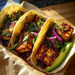 Three Spicy Honey Halloumi Tacos filled with avocado, red onion, and cilantro, drizzled with spicy honey sauce.