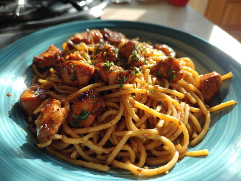 A plate of Sticky Smoky Garlic Butter Chicken Pasta with glazed chicken pieces and fresh herbs.