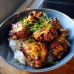 A bowl of Vietnamese Lemongrass Chicken wings served over white rice, garnished with fresh herbs.