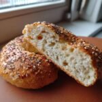 A sliced bagel with almond flour and cottage cheese, topped with sesame and poppy seeds, showing the interior texture.