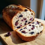 A loaf of blueberry lemon sourdough bread, sliced open to show the blueberries inside.