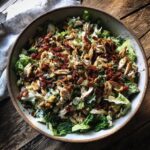 Overhead shot of a bowl of Chicken Salad Recipe with lettuce, shredded chicken, bacon bits, and dressing.