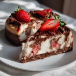 A slice of Chocolate Strawberry Swirl Cheesecake topped with fresh strawberries on a white plate.