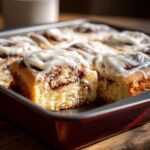 Close-up of Cinnamon Roll Bars with white icing in a red baking pan, showing the cinnamon swirl.