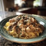 Delicious crockpot chicken recipe with mushrooms and creamy sauce served over pasta, garnished with parsley.