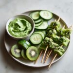 Cucumber skewers with green dip and kiwi slices, a vibrant addition to green foods for party.