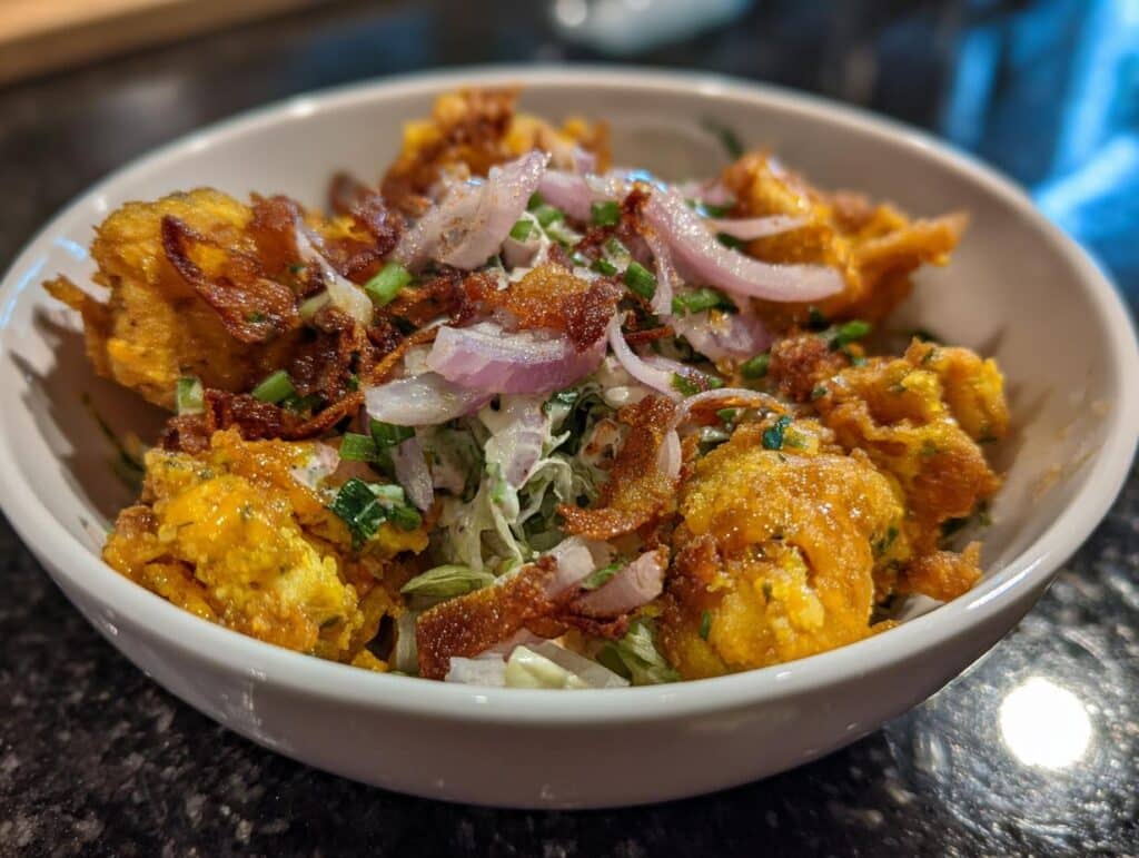 A bowl of easy chicken salad with fried chicken pieces, red onions, and green onions.