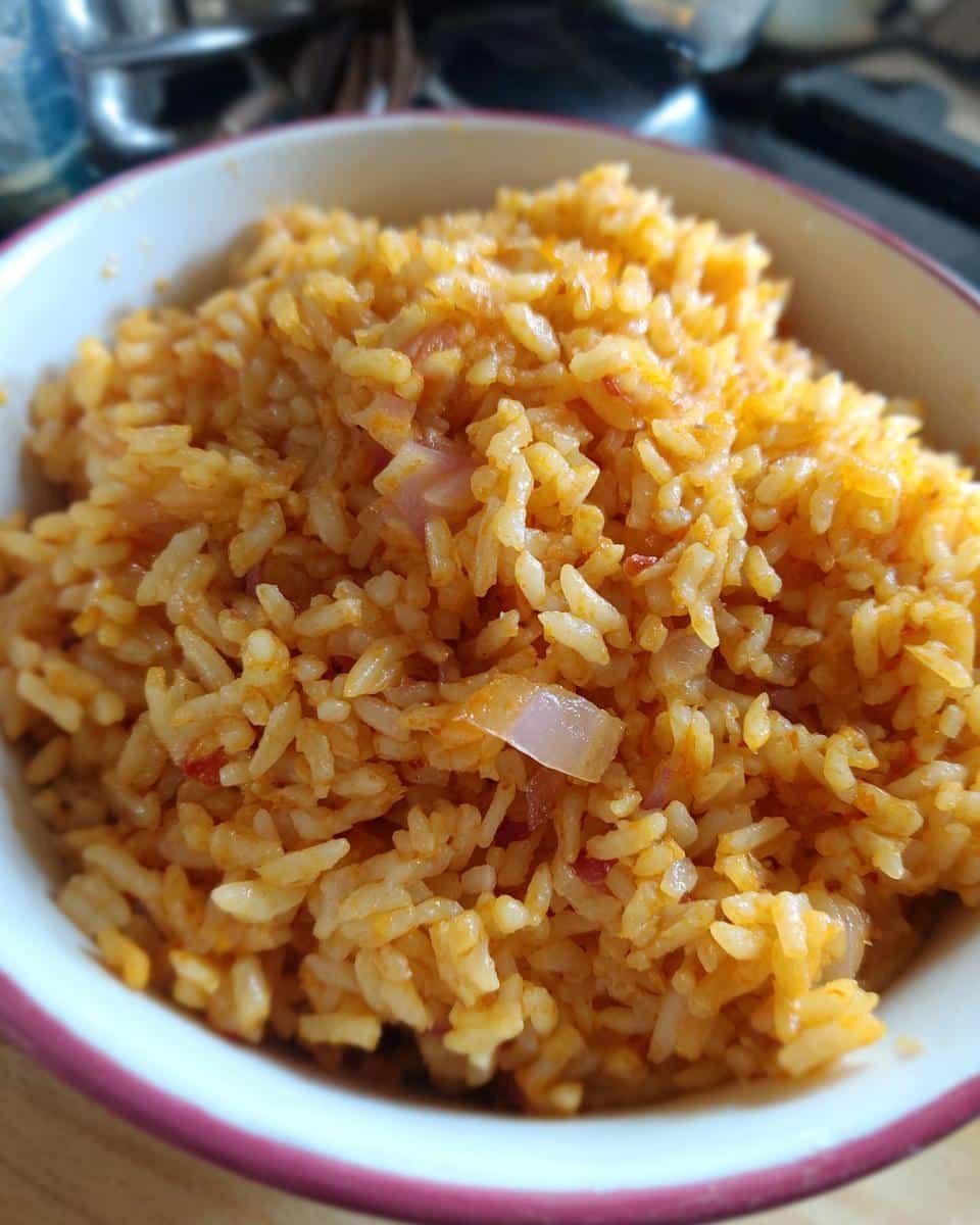 Easy Mexican Rice in a Rice Cooker: 30 Min & Fail-Proof 6 Close-up of a bowl of fluffy easy Mexican rice in a rice cooker, showing visible onions and reddish color.