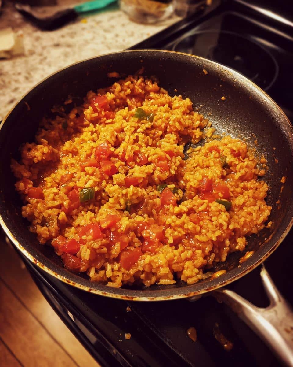 Devastatingly Easy Mexican Rice with Rotel in 30 Minutes 6 A pan filled with easy Mexican rice with Rotel, featuring rice, tomatoes, and green peppers.