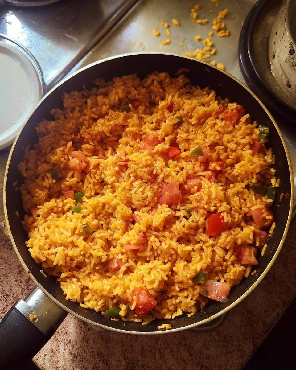 Devastatingly Easy Mexican Rice with Rotel in 30 Minutes 9 Overhead shot of easy mexican rice with rotel, tomatoes, and green peppers in a skillet.