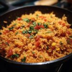 Close-up of easy Mexican rice recipe in a skillet, garnished with cilantro, tomatoes, and corn.