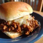 A delicious French Onion Beef Sloppy Joes sandwich with melted cheese on a blue plate.