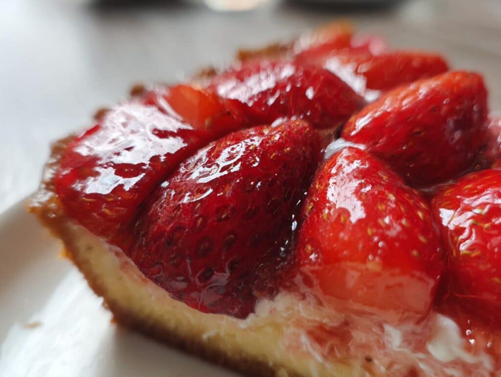 Close-up of a slice of strawberry tart, showcasing fresh strawberry recipes with a creamy filling and glazed topping.