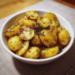 A bowl of delicious Greek Lemon Potatoes, seasoned with herbs and spices, ready to serve.