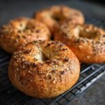 Close-up of several high protein bagels air fryer, seasoned, on a wire rack.