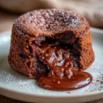Close-up of a Hot Chocolate Cake with a molten chocolate center oozing out, dusted with powdered sugar.