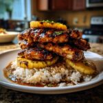 A towering Huli Huli Chicken Stack featuring grilled chicken, pineapple, and rice on a white plate.