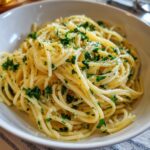 Bowl of Lemon Capellini Salad, featuring pasta, lemon sauce, and fresh parsley.