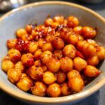 Close-up of Marry Me Chickpeas in a bowl, coated in a rich, savory sauce with red pepper flakes.