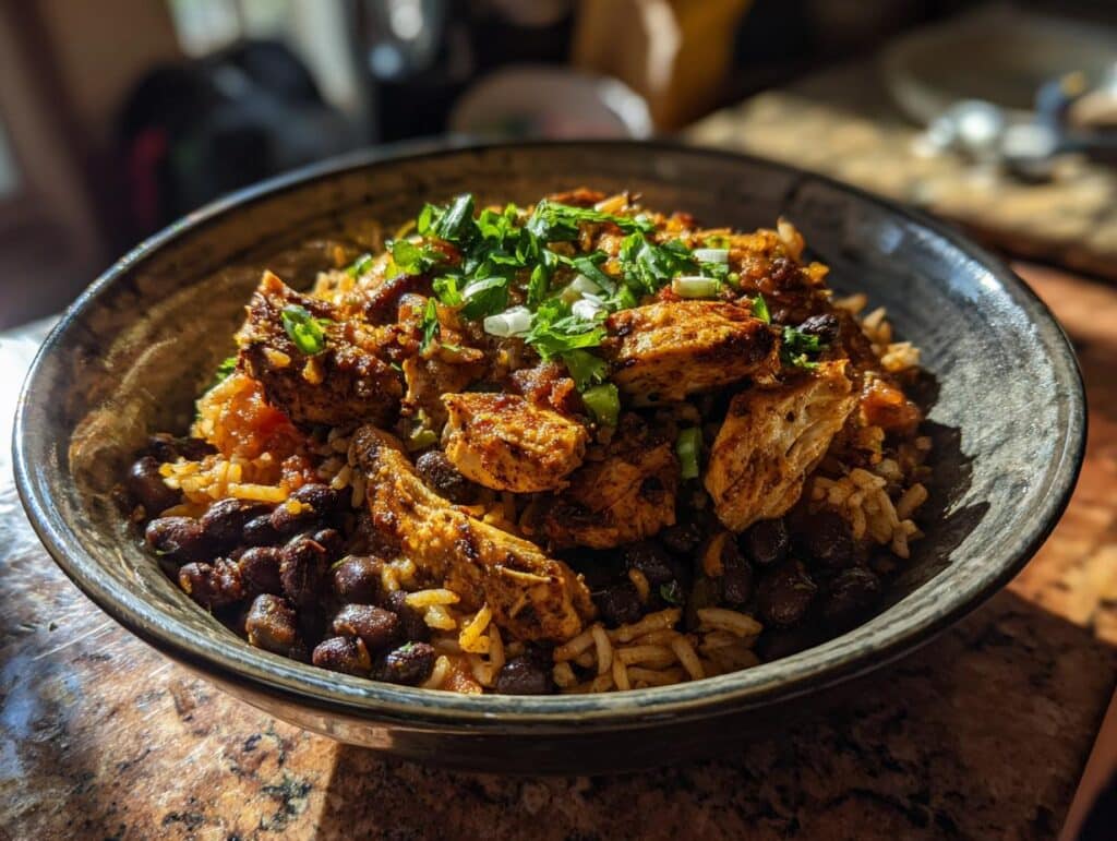 A bowl of Mexican chicken, black beans, and rice, garnished with fresh cilantro and green onions.