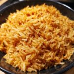 Close-up of fluffy Mexican rice in a rice cooker recipe in a black bowl, ready to serve.