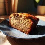 A slice of moist banana bread on a blue plate, showcasing its texture and golden crust.