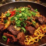A bowl of delicious Mongolian Beef Noodles with tender beef, noodles, and green onion garnish.