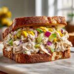 A delicious OLD FASHIONED CHICKEN SALAD sandwich with celery, red onion, and mustard on toasted bread.