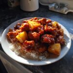 A plate of pineapple chicken and rice on blackstone, featuring glazed chicken and pineapple chunks over fluffy white rice.