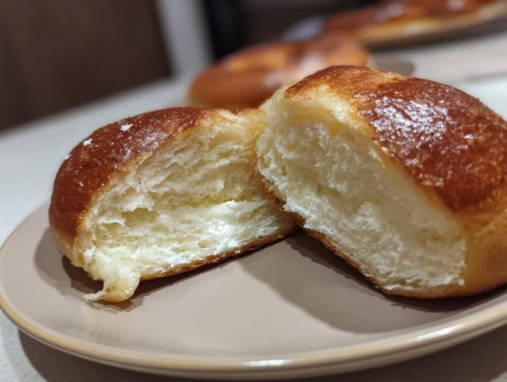 A protein bagel with greek yogurt, cut in half to show the soft interior texture.