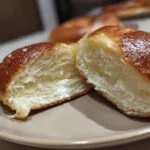 A protein bagel with greek yogurt, cut in half to show the soft interior texture.