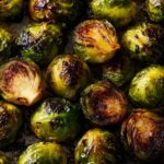 Close-up of golden brown Roasted Brussels Sprouts on a baking sheet, showing their crispy texture.