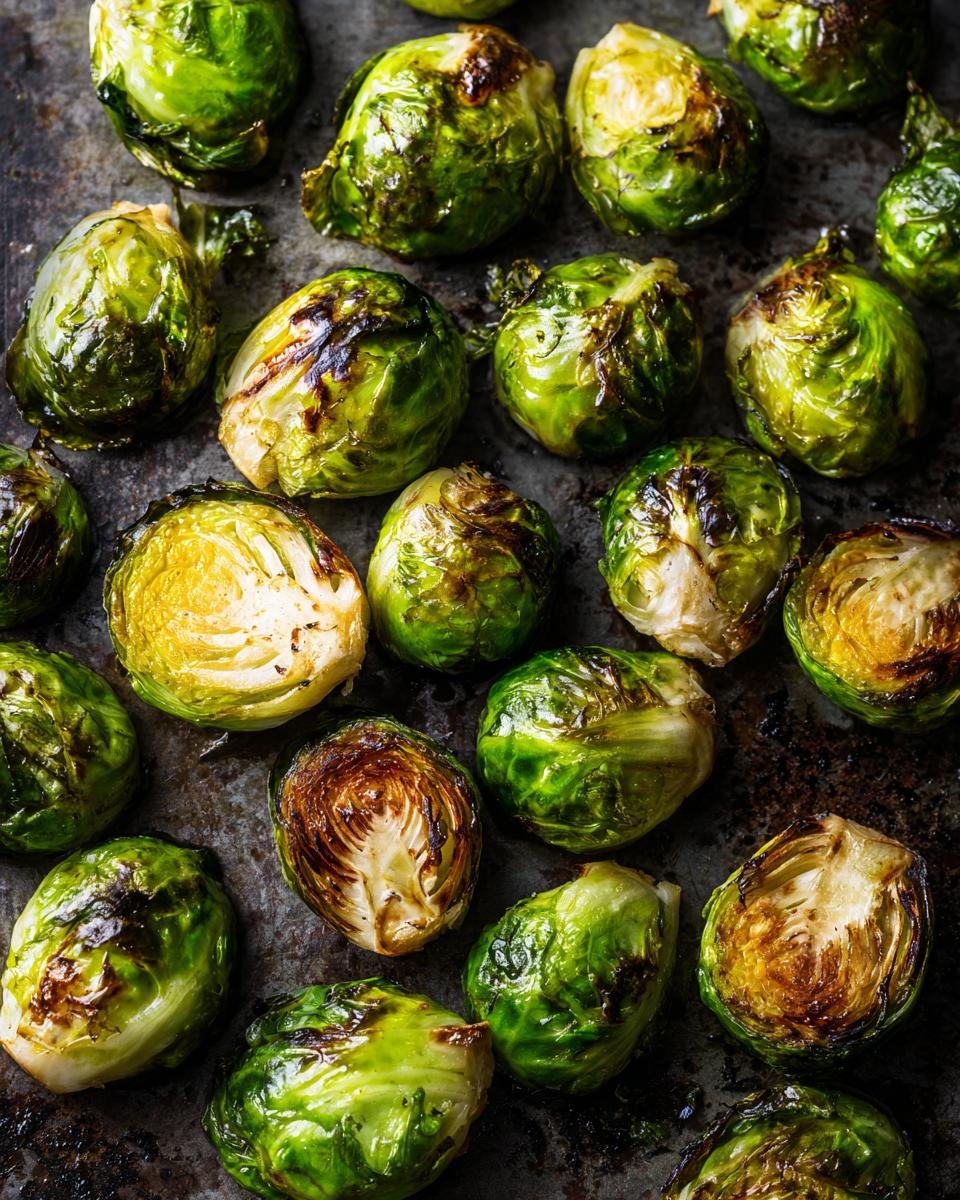 Roasted Brussels Sprouts: 4 Ingredient Magic Recipe 6 Close-up of golden brown Roasted Brussels Sprouts on a dark baking sheet, ready to eat.